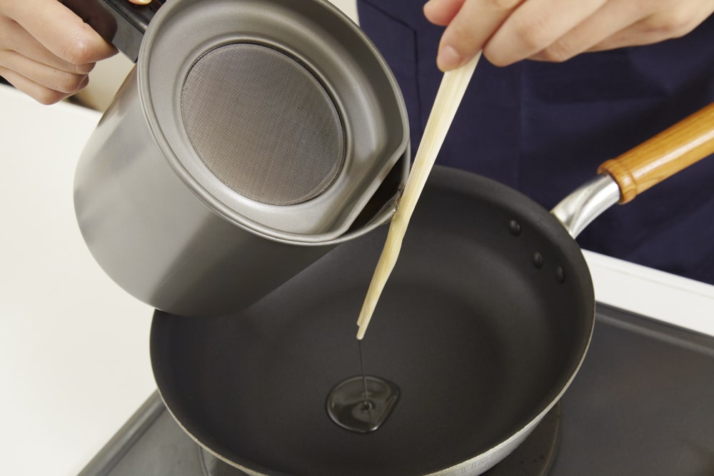 オイルポットからフライパンに油を注ぐ